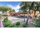 Community center exterior with fountain, outdoor seating, lush landscaping, and mature trees at 8377 S Mountain Air Ln, Gold Canyon, AZ 85118