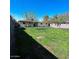 Beautiful backyard featuring a lush green lawn, mature trees, and a charming single-story home under a clear blue sky at 1017 S Lola Ln, Tempe, AZ 85281