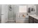 Bright bathroom features a glass shower, soaking tub, and gray vanity with a decorative glass block window at 10932 E Bella Via --, Mesa, AZ 85212