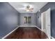 Bedroom featuring dark gray walls, wood floors, ceiling fan, and bright window at 1210 E Azure Sea Ln, Gilbert, AZ 85234