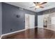 Spacious bedroom featuring dark gray walls, wood floors, ceiling fan, and adjacent hallway at 1210 E Azure Sea Ln, Gilbert, AZ 85234