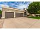 Two-car garage with a neutral color scheme, complemented by lush landscaping and a well-maintained lawn at 1210 E Azure Sea Ln, Gilbert, AZ 85234