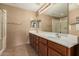 Bathroom with double sinks, wood cabinets, large mirror, and walk-in shower with glass door at 14000 N 94Th St # 3147, Scottsdale, AZ 85260