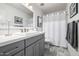 Modern bathroom with gray vanity, decorative tile floor, framed artwork, and shower with curtain at 15027 N 61St Pl, Scottsdale, AZ 85254