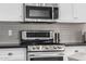 Stainless steel stove and microwave with tile backsplash and dark countertop in kitchen at 15027 N 61St Pl, Scottsdale, AZ 85254