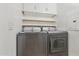 Laundry room with front loading washer and dryer, overhead shelving, and painted white at 1701 E Colter St # 311, Phoenix, AZ 85016