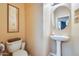 A simple powder room featuring a pedestal sink, a round mirror and standard toilet at 18360 N 169Th Ave, Surprise, AZ 85374