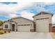 Charming single-story home featuring a three car garage, desert landscaping, and a stone facade at 18988 W Cortez St, Surprise, AZ 85388
