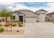 Charming single-story home featuring a three car garage, desert landscaping, and a stone facade at 18988 W Cortez St, Surprise, AZ 85388