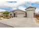 Charming single-story home featuring a three car garage, desert landscaping, and a stone facade at 18988 W Cortez St, Surprise, AZ 85388