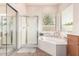 Bathroom with a corner soaking tub, a glass enclosed shower, and natural light from the large window at 2212 W Calle De Las Estrella St, Phoenix, AZ 85085