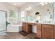 Bright bathroom featuring dual vanities, a garden tub, a walk-in shower and a large mirror at 2212 W Calle De Las Estrella St, Phoenix, AZ 85085