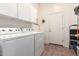 Well-lit laundry room featuring large capacity washer and dryer and ample cabinet space at 2212 W Calle De Las Estrella St, Phoenix, AZ 85085