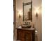 Bathroom with unique rock sink, wood cabinet, and sconce lighting at 25031 N Paso Trl, Scottsdale, AZ 85255
