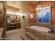 Luxurious bathroom showcasing a soaking tub with shuttered windows and a vanity with a makeup area at 25031 N Paso Trl, Scottsdale, AZ 85255