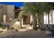 Inviting front entrance with an arched entryway, rustic double doors, and desert landscaping at 25031 N Paso Trl, Scottsdale, AZ 85255
