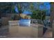 Outdoor kitchen area features a built-in grill with tile accents surrounded by lush landscaping at 25031 N Paso Trl, Scottsdale, AZ 85255
