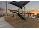 Community playground with climbing structures, slide, sun shades, and sidewalks in a modern planned community at 25443 W Graham Trl, Buckeye, AZ 85326