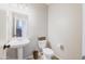 A stylish powder room with a pedestal sink, toilet, and neutral color scheme at 30419 N Plantation Dr, San Tan Valley, AZ 85143