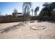 Landscaped backyard featuring a rock-lined fire pit, mature trees, and ample space for outdoor activities at 3721 N Brindley Ave, Litchfield Park, AZ 85340