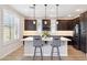 Modern kitchen island with barstool seating, pendant lighting, white countertops, and dark cabinets at 5100 E Rancho Paloma Dr # 2061, Cave Creek, AZ 85331