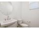 Well-lit powder room with a pedestal sink, round mirror, and a modern toilet at 7417 W Buckhorn Trl, Peoria, AZ 85383