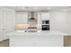 Well-appointed kitchen with white cabinets, stainless steel range hood, a large island, and modern lighting at 7417 W Buckhorn Trl, Peoria, AZ 85383