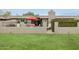 The backyard features a grass lawn, patio, red umbrella, and a metal fence at 8187 E Del Caverna Dr, Scottsdale, AZ 85258