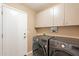 Functional laundry area with side-by-side washer/dryer and overhead cabinets at 11731 N 91St Pl, Scottsdale, AZ 85260