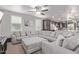 Open-concept living room with a gray sofa, ceiling fan, and lots of natural light at 16268 W Cortez St, Surprise, AZ 85379