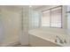 Bright white bathroom showcasing a soaking tub with a glass block privacy wall at 16462 W Rowel Rd, Surprise, AZ 85387