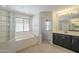 Bright bathroom featuring a soaking tub and dual sink vanity with dark cabinetry at 16462 W Rowel Rd, Surprise, AZ 85387
