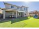Back of house with artificial grass, play structure, and covered patio seating area at 16462 W Rowel Rd, Surprise, AZ 85387