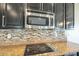 A kitchen's cooktop is featured with dark cabinets, granite countertops, stainless steel appliances and tile backsplash at 16462 W Rowel Rd, Surprise, AZ 85387