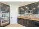 A kitchen features dark cabinetry, stainless steel appliances, granite countertops and ceramic tile backsplash at 16462 W Rowel Rd, Surprise, AZ 85387