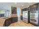 A kitchen is showcased with dark cabinetry, stainless steel appliances and view to an adjacent living space at 16462 W Rowel Rd, Surprise, AZ 85387