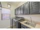 Laundry room featuring washer and dryer with dark cabinets and a sink at 16462 W Rowel Rd, Surprise, AZ 85387