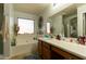 Bright bathroom showcasing a garden tub under a window, vanity with wood cabinets, and large mirror at 1844 E Angelica St, Casa Grande, AZ 85122