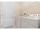 Laundry room featuring newer washer and dryer units with storage shelf and exterior door at 18668 N Lariat Ct, Surprise, AZ 85387