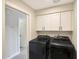Bright laundry area with modern front-load washer, dryer, and overhead white cabinets for storage at 1960 Leisure World --, Mesa, AZ 85206