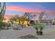 Charming desert home with a welcoming entrance, lush landscaping, and warm exterior lighting at twilight at 30600 N Pima Rd # 76, Scottsdale, AZ 85266