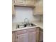Well-lit kitchen with a stainless steel sink, neutral countertops, and light wood cabinets at 311 E Lancaster Ct, Florence, AZ 85132