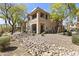 Exterior view of a two-story home with a landscaped yard, stone ground covering, and mature trees at 5450 E Mclellan Rd # 102, Mesa, AZ 85205