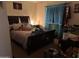 Cozy bedroom with a dark wood bed frame, soft lighting, and a window with blue curtains at 5684 S 237Th Dr, Buckeye, AZ 85326