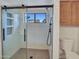 Modern bathroom with a glass-enclosed shower, tiled walls, and a window offering natural light at 6704 W Topeka Dr, Glendale, AZ 85308