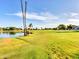 Picturesque golf course with a serene lake and tall palm trees under a blue sky at 6704 W Topeka Dr, Glendale, AZ 85308
