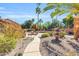Serene backyard with a charming water fountain, lush desert landscape, and a refreshing pool in the distance at 8935 E Larkspur Dr, Scottsdale, AZ 85260