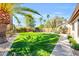 Spacious backyard featuring lush green grass, mature trees, and a charming desert landscape at 8935 E Larkspur Dr, Scottsdale, AZ 85260