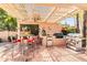 Well-equipped outdoor kitchen with built-in grill and mini fridge, complemented by bar seating and a shade pergola at 8935 E Larkspur Dr, Scottsdale, AZ 85260