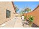 Functional side yard with a greenhouse, utility access, and a walkway lined with mature greenery at 8935 E Larkspur Dr, Scottsdale, AZ 85260